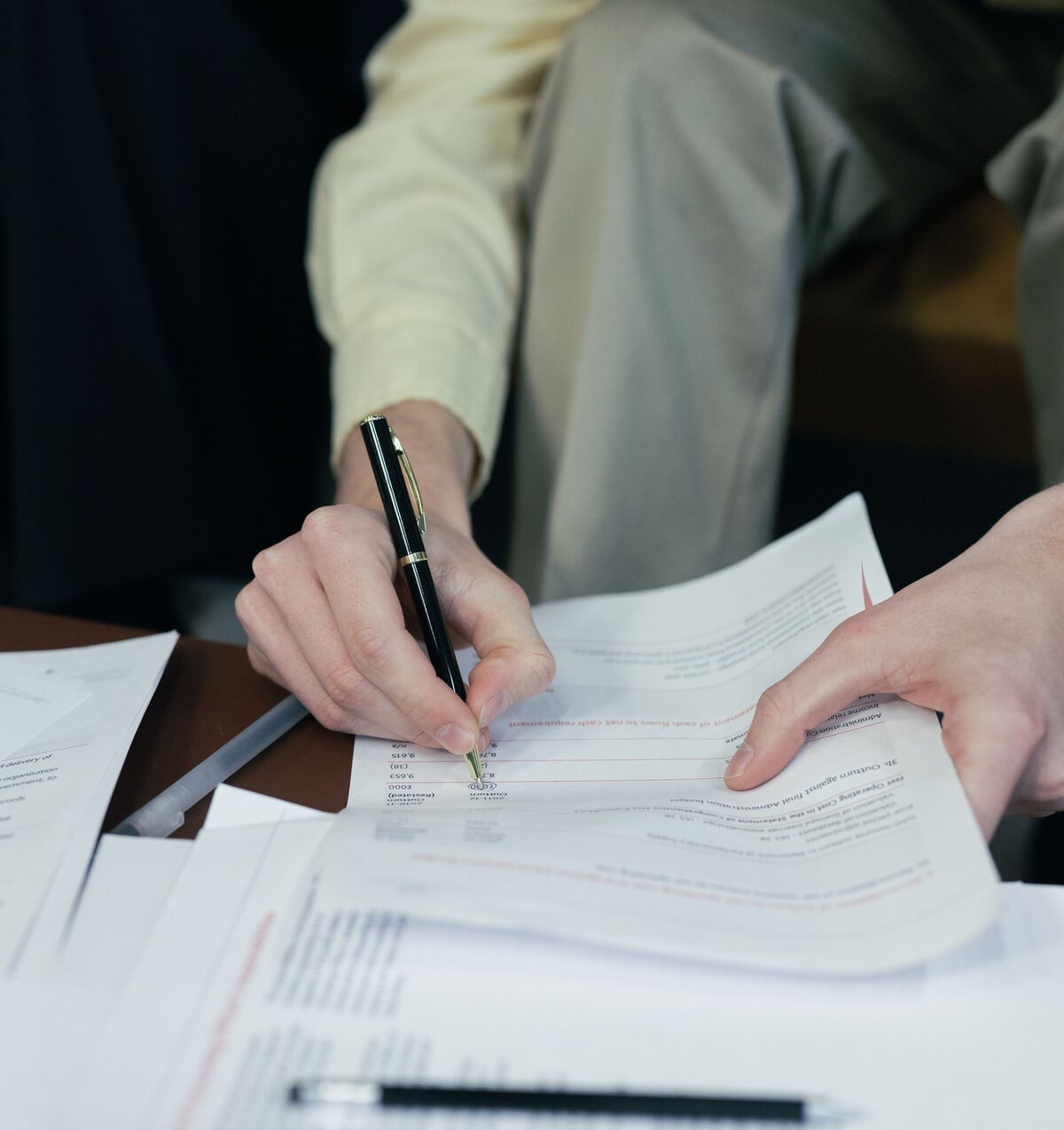 Two specialists at a desk annotating a printed claim document with a pen